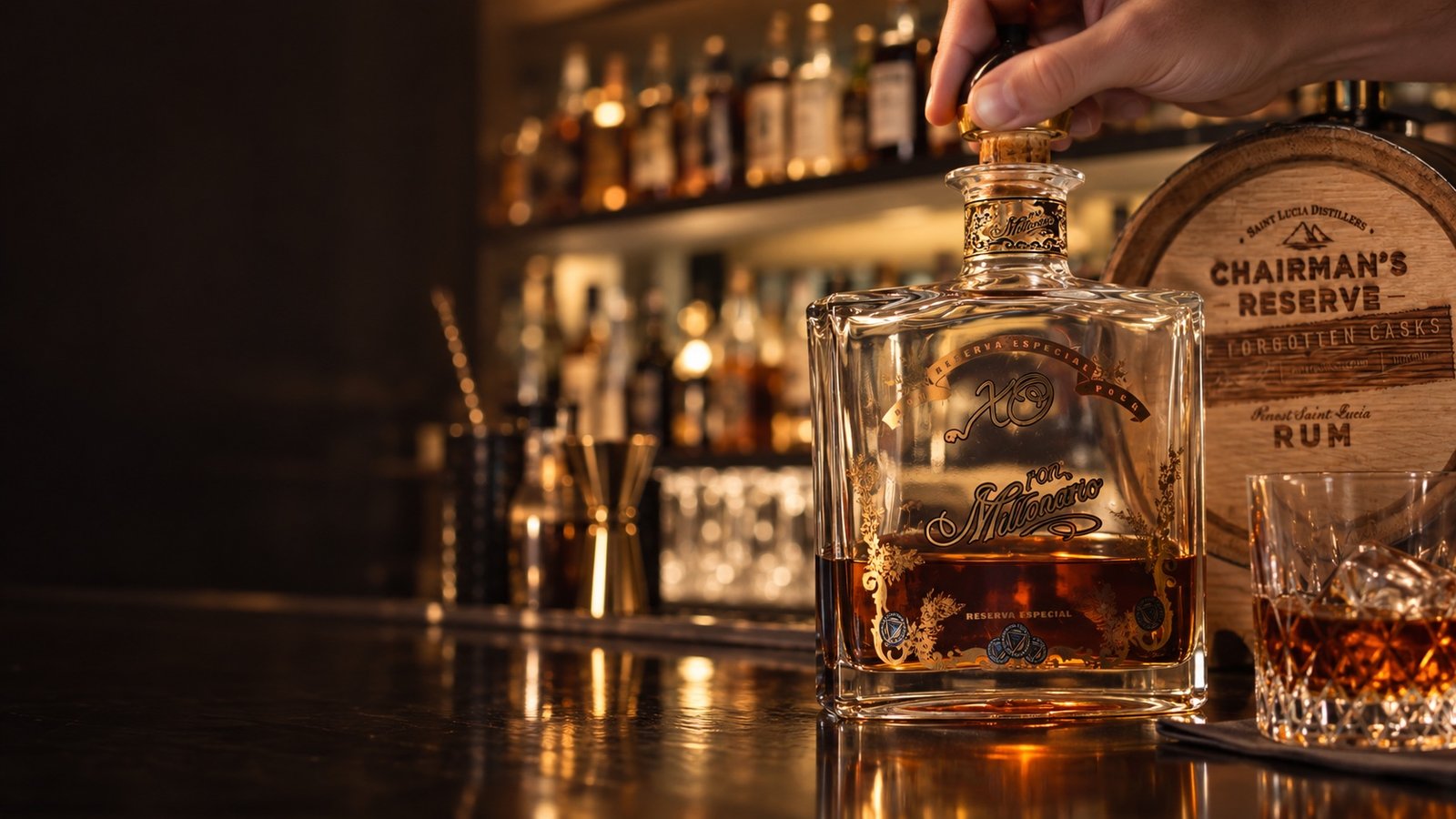 Editorial composition of a Ron Millonario bottle being opened beside a Chairman's Reserve rum cask and a glass
