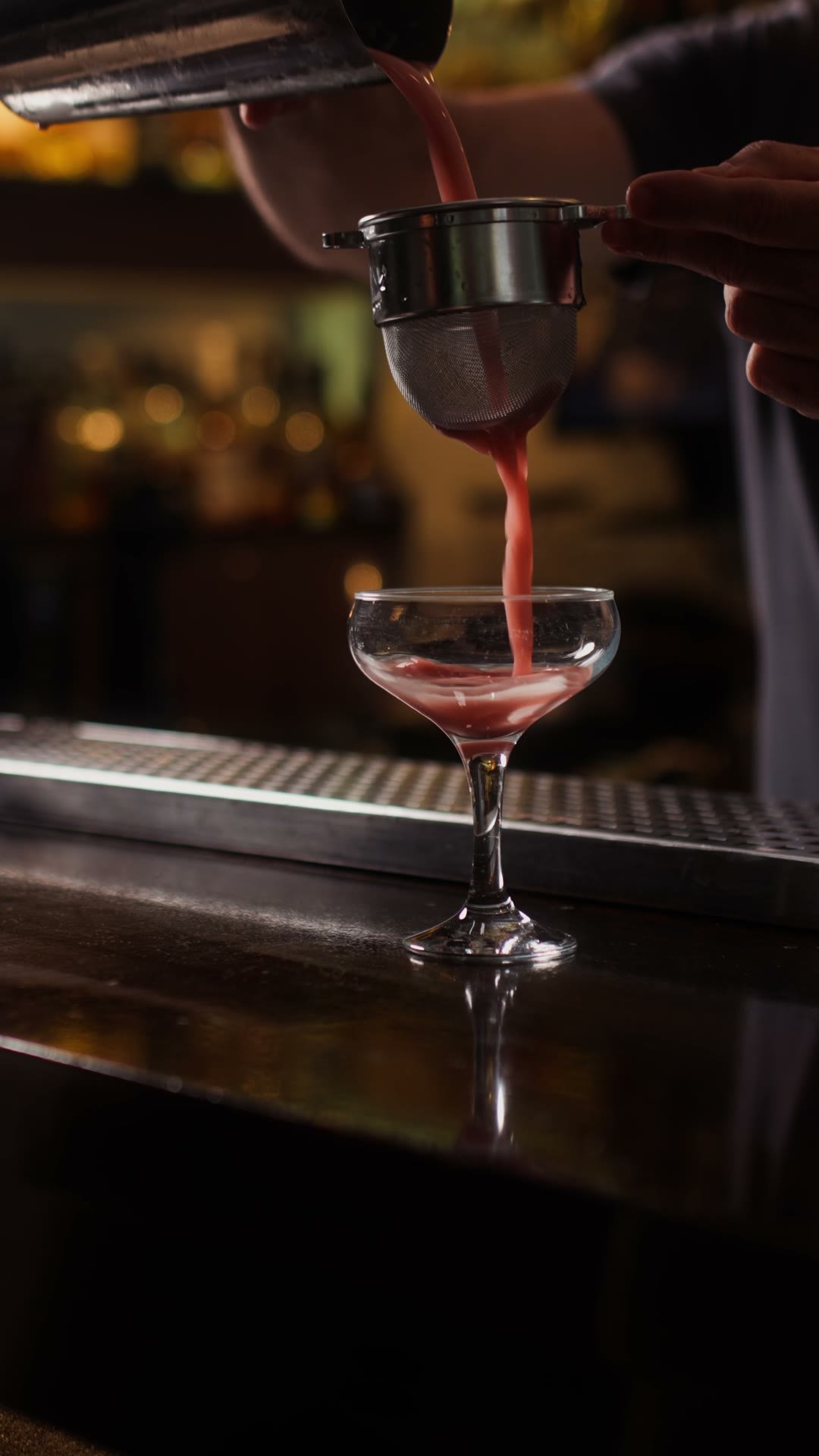 A Madison signature cocktail strained into a coupe at the dark bar